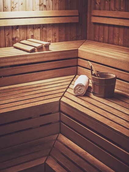 Finnische Sauna aus Holz mit einem Aufgusseimer, Kelle und einem Saunatuch auf der Liegefläche. | © Davos Klosters Mountains