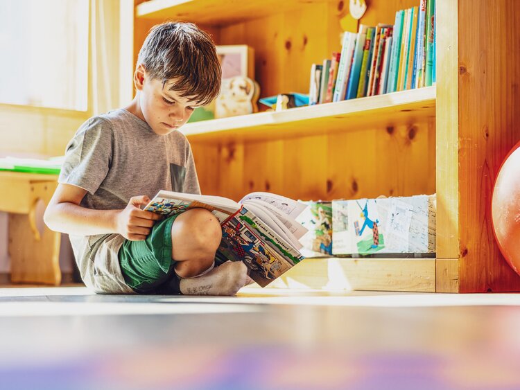 Ein Junge sitzt im Globi Kids Club und ist in einem Buch von Globi vertieft. | © DDO - davos.ch | Martin Bissig