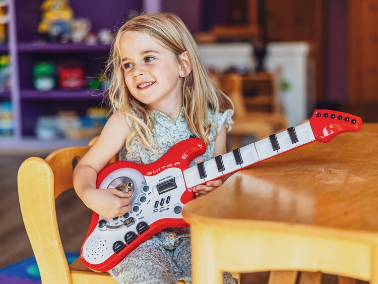 Ein Mädchen spielt auf einer roten Gitarre im Globi Kids Club im Hotel Waldhuus in Davos. | © DDO - davos.ch | Martin Bissig
