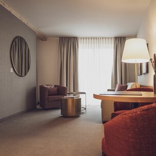 Hotelzimmer mit Salontisch, Vorhängen und Stehlampe  | © Davos Klosters Mountains 