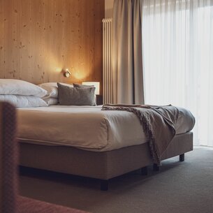 Doppelbett mit Bettwäsche und Vorhängen  | © Davos Klosters Mountains 